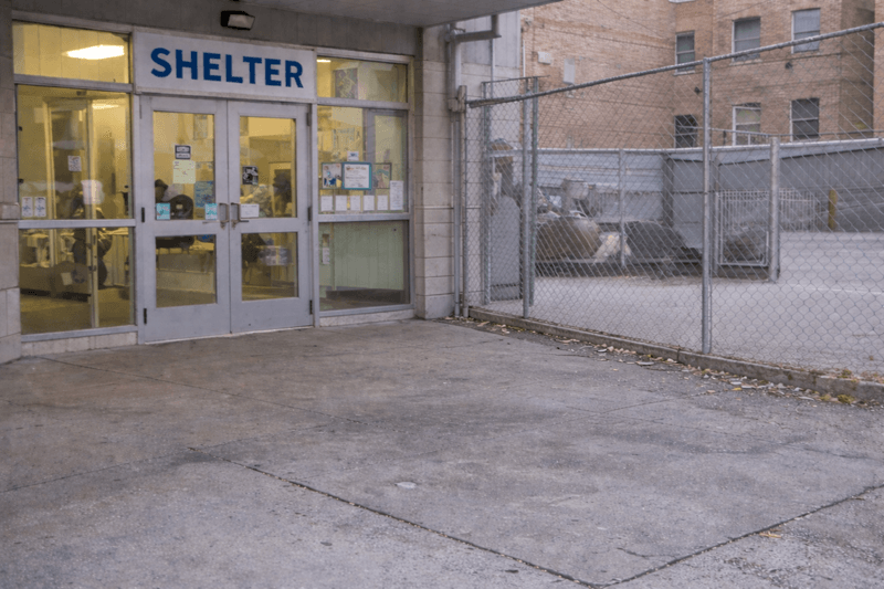 Homeless shelter entrance with secure glass doors and fenced exterior area